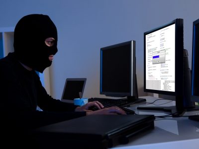 Masked,Hacker,Wearing,A,Balaclava,Sitting,At,A,Desk,Downloading